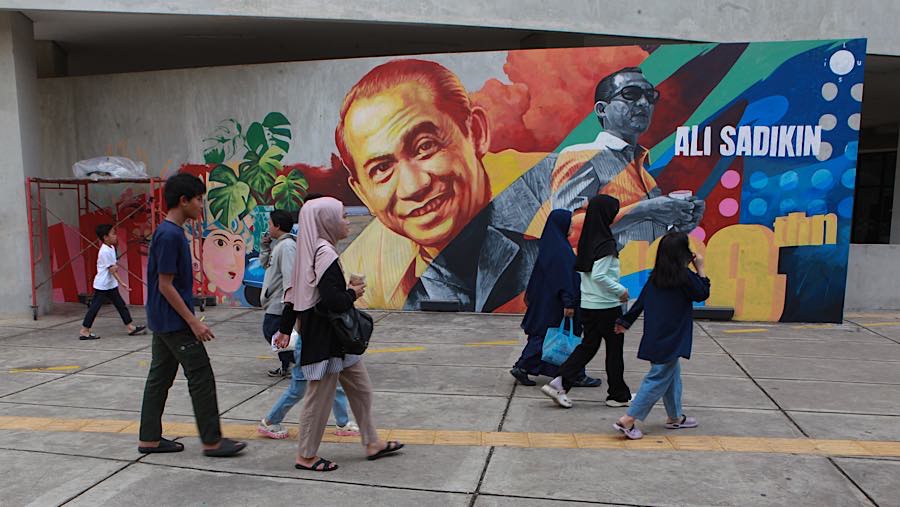 Pengunjung berjalan dengan latar mural Ali Sadikin di Taman Ismail Marzuki, Jakarta, Rabu (8/7/2026).(Bloomberg Technoz/Andrean Kristianto)