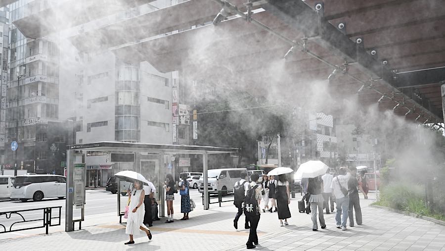 Pejalan kaki di bawah kabut pendingin saat suhu tinggi di distrik Yurakucho, Tokyo, Jepang, Selasa (14/7/2026). (Soichiro Koriyama/Bloomberg)