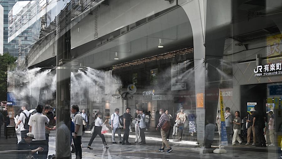 Warga di bawah kabut pendingin saat suhu tinggi di depan stasiun JR East Yurakucho, Tokyo, Jepang, Selasa (14/7/2026). (Soichiro Koriyama/Bloomberg)