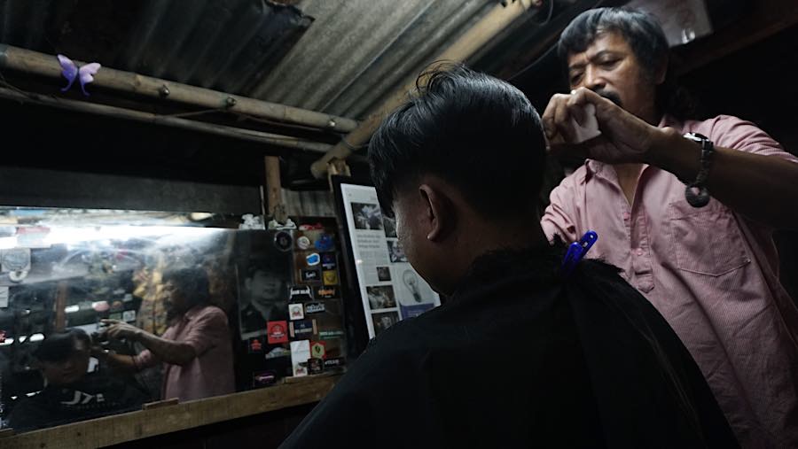 Supri (62) melayani pelanggan di Pangkas Rambut Pemuda, Jalan Pemuda, Bogor, Jawa Barat, Kamis (16/7/2026). (Bloomberg Technoz/Andrean Kristianto)