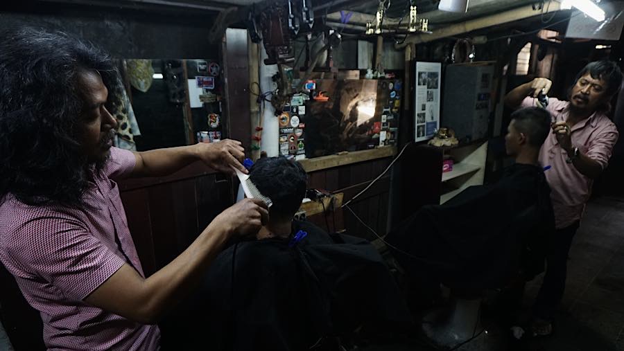 Bersama rekannya, Supri setiap harinya melayani pelanggan yang ingin memotong rambut di tempat usahanya yang sederhana. (Bloomberg Technoz/Andre)