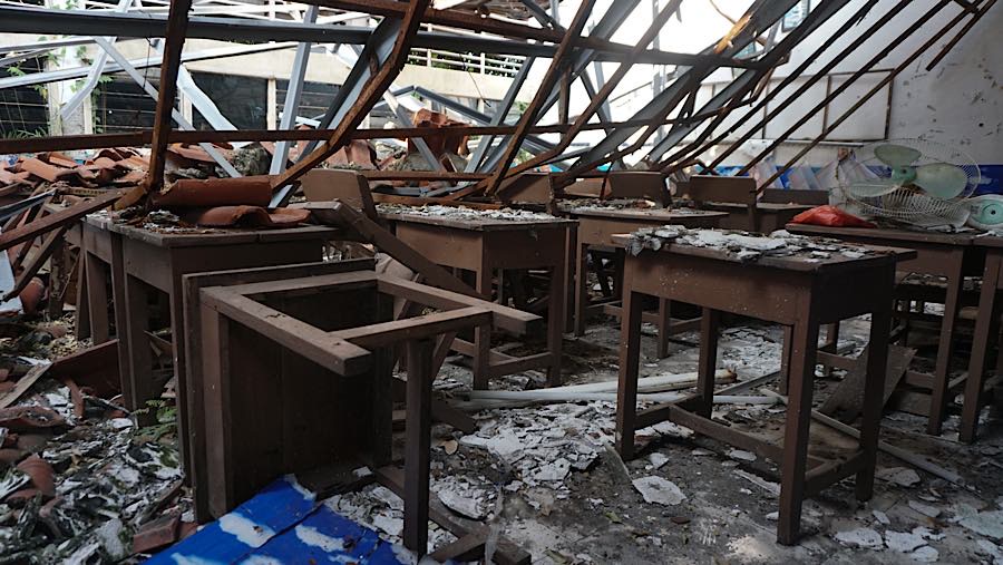 Rangka atap bangunan terlihat ambruk dan menyisakan puing-puing genteng serta material besi yang berserakan di dalam kelas. (Bloomberg Technoz/Andre)