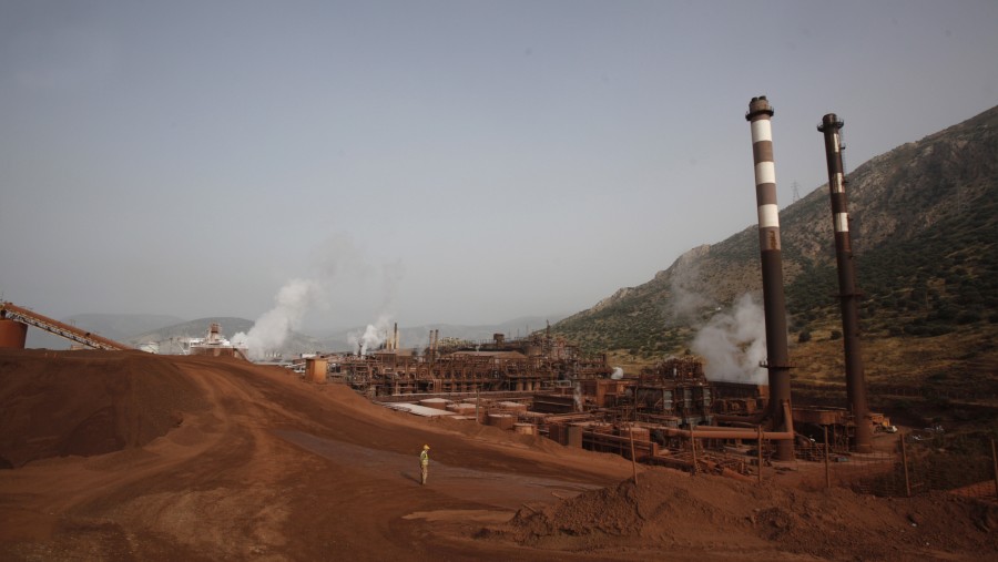 Seorang pekerja berdiri di area batuan bauksit merah di fasilitas produksi Aluminum of Greece SA./Bloomberg-Kostas Tsironis