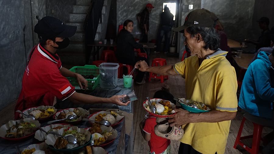 Warga mengambil makanan di rumah makan gratis di jalan Raya Pekayon, Bekasi, Kamis (23/7/2026). (Bloomberg Technoz/Andrean Kristianto)