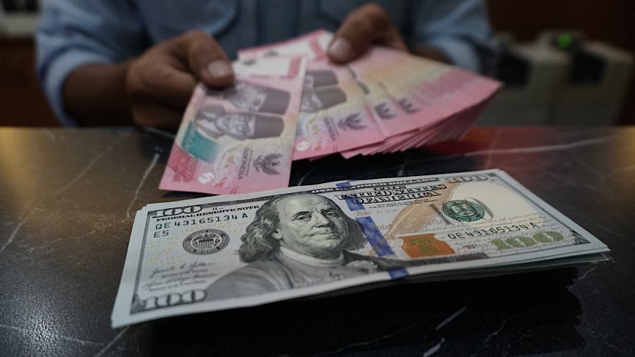 Karyawan merapihkan mata uang rupiah dan dolar AS di tempat penukaran mata uang di Jakarta, Senin (27/7/2026). (Bloomberg Technoz/Andrean Kristianto)