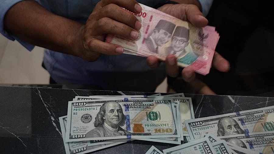 Karyawan merapihkan mata uang rupiah dan dolar AS di tempat penukaran mata uang di Jakarta, Senin (27/7/2026). (Bloomberg Technoz/Andrean Kristianto)
