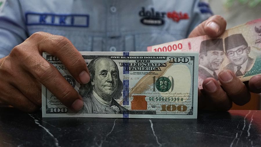 Karyawan merapihkan mata uang dolar AS dan rupiah di tempat penukaran mata uang di Jakarta, Senin (27/7/2026). (Bloomberg Technoz/Andrean Kristianto)
