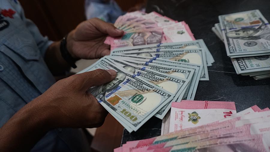 Karyawan merapihkan mata uang rupiah dan dolar AS di tempat penukaran mata uang di Jakarta, Senin (27/7/2026). (Bloomberg Technoz/Andrean Kristianto)
