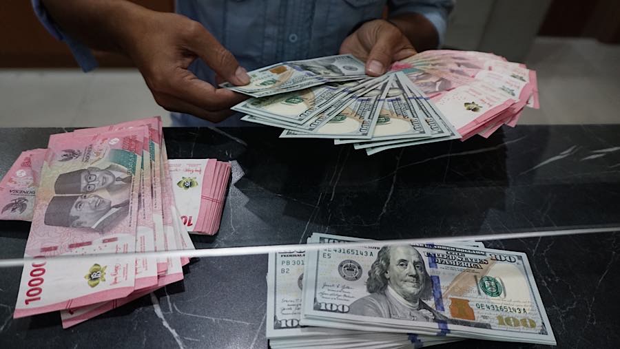 Karyawan merapihkan mata uang rupiah dan dolar AS di tempat penukaran mata uang di Jakarta, Senin (27/7/2026). (Bloomberg Technoz/Andrean Kristianto)
