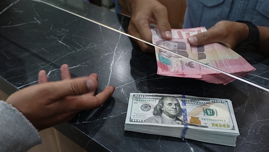 Karyawan menghitung mata uang rupiah di tempat penukaran mata uang di Jakarta, Senin (27/7/2026). (Bloomberg Technoz/Andrean Kristianto)