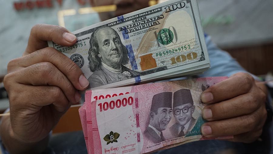 Karyawan merapihkan mata uang rupiah dan dolar AS di tempat penukaran mata uang di Jakarta, Senin (27/7/2026). (Bloomberg Technoz/Andrean Kristianto)