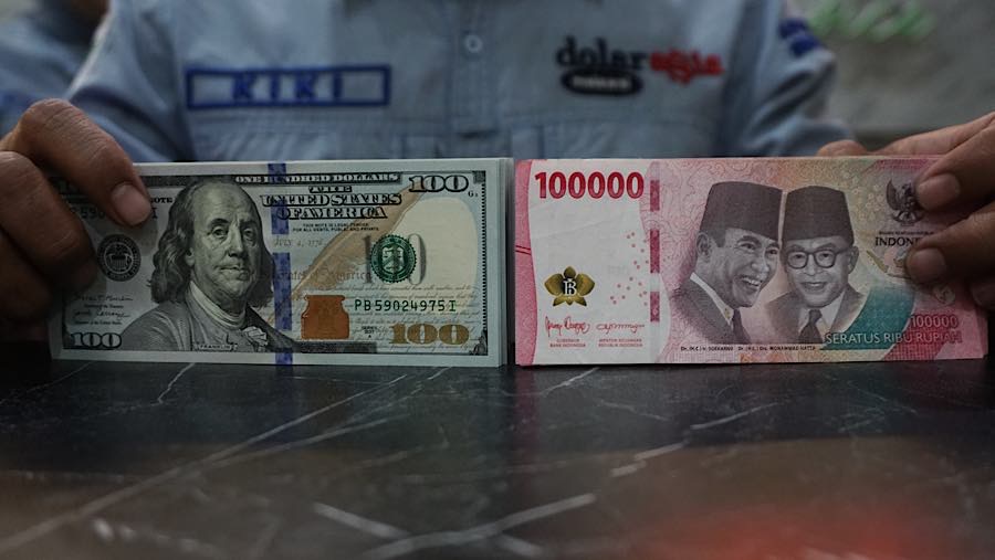 Karyawan merapihkan mata uang rupiah dan dolar AS di tempat penukaran mata uang di Jakarta, Senin (27/7/2026). (Bloomberg Technoz/Andrean Kristianto)