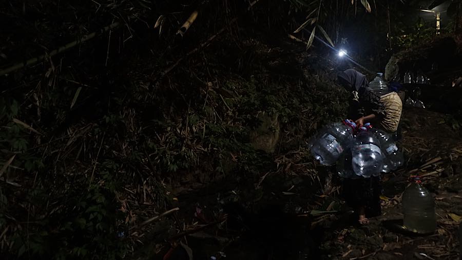 Matahari mulai tenggelam, warga Kampung Gunung Batur 2, Cilegon, Banten, masih berjalan menuju dasar Sungai Sumur Tengah. (Bloomberg Technoz/Andrean)