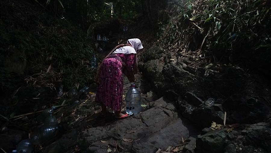 Setelah terisi, air tersebut harus kembali diangkat melewati jalur bebatuan hingga menuju rumah. (Bloomberg Technoz/Andrean Kristianto)