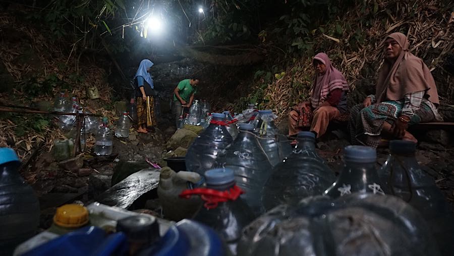 Walau banyak nyamuk para ibu-ibu berkumpul sambil menunggu galon yang ia bawa terisi. (Bloomberg Technoz/Andrean Kristianto)