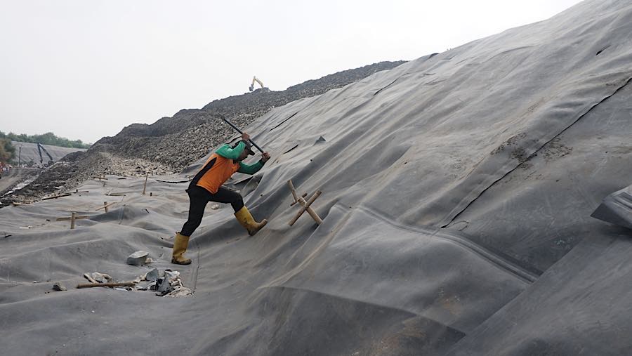 Petugas memasang patok pada geomembran untuk menutup sampah di TPST Bantargebang, Bekasi, Selasa (4/8/2026). (Bloomberg Technoz/Andrean Kristianto)