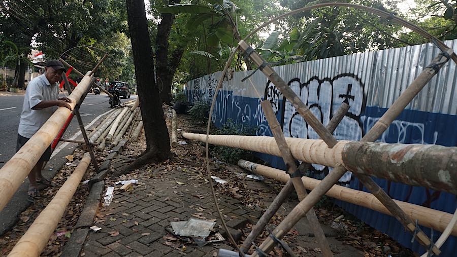 Pekerja mengamplas kulit batang pohon pinang di kawasan Manggarai, Jakarta, Selasa (11/8/2026). (Bloomberg Technoz/Andrean Kristianto)