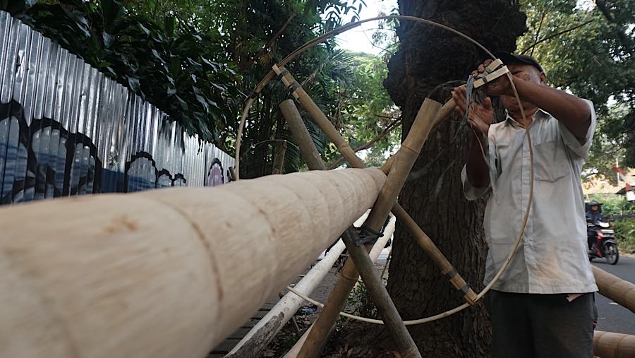 Pekerja merapihkan batang pohon pinang di kawasan Manggarai, Jakarta, Selasa (11/8/2026). (Bloomberg Technoz/Andrean Kristianto)