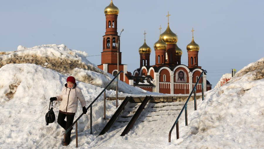 Seorang warga menuruni jalan bersalju di dekat Gereja Kelahiran Kristus di Nizhnevartovsk, Rusia./Bloomberg-Andrey Rudakov