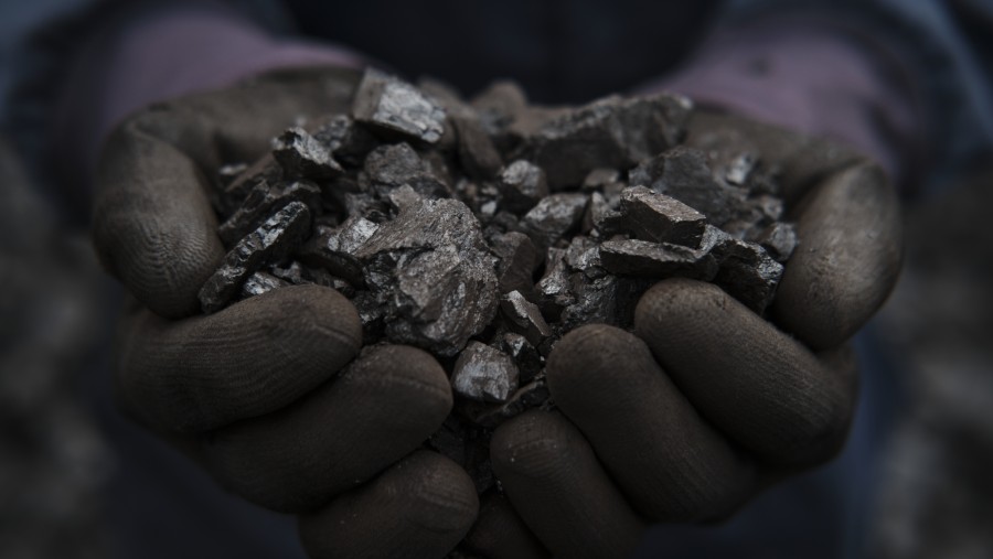 Foto close-up seseorang yang memegang segenggam batu bara kokas. (Ferley Ospina/Bloomberg)
