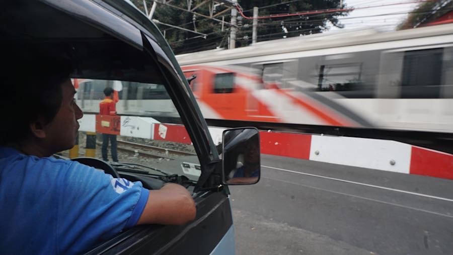 Sopir angkot menunggu saat rangkaian KRL melintas di perlintasan Stasiun Karet, Jakarta, Senin (31/8/2026). (Bloomberg Technoz/Andrean Kristianto)