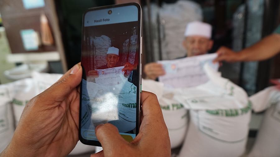 Petugas kemudian memverifikasi identitas penerima dengan mendata dan memotret sebelum bantuan diserahkan. (Bloomberg Technoz/Andrean Kristianto)