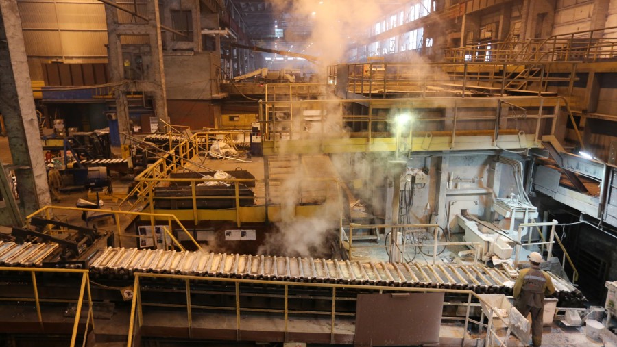 Seorang pekerja mengamati ingot aluminium yang sedang mendingin di dalam cetakannya di pabrik pengecoran./Bloomberg-Andrey Rudakov