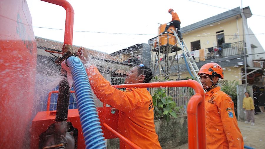 Personel BPBD Jakarta Selatan mengisi air warga yang terdampak kekeringan di Lenteng Agung, Jumat (18/9/2026). (Bloomberg Technoz/Andrean Kristianto)