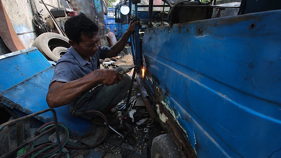 Mekanik memperbaiki bajaj di Jalan Makmur, Duri Pulo, Gambir, Jakarta Pusat, Senin (21/9/2026) (Bloomberg Technoz/Andrean Kristianto)