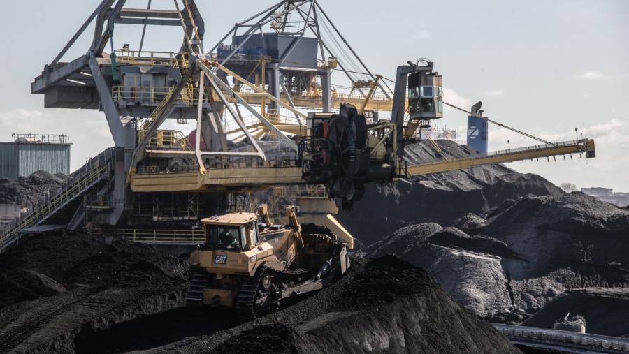 Sebuah buldoser sedang beroperasi di atas tumpukan batu bara di samping stacker-reclaimer./Bloomberg-Peter Boer
