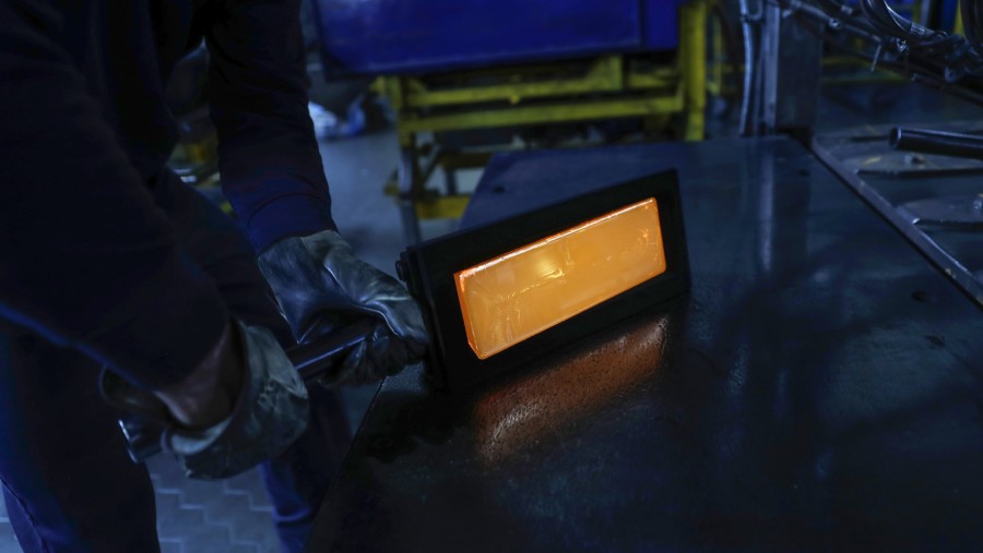 Pekerja mengenakan pakaian pelindung saat mengeluarkan batangan emas yang baru dicetak dari cetakan selama proses pemurnian./Bloomberg-Stefan Wermuth