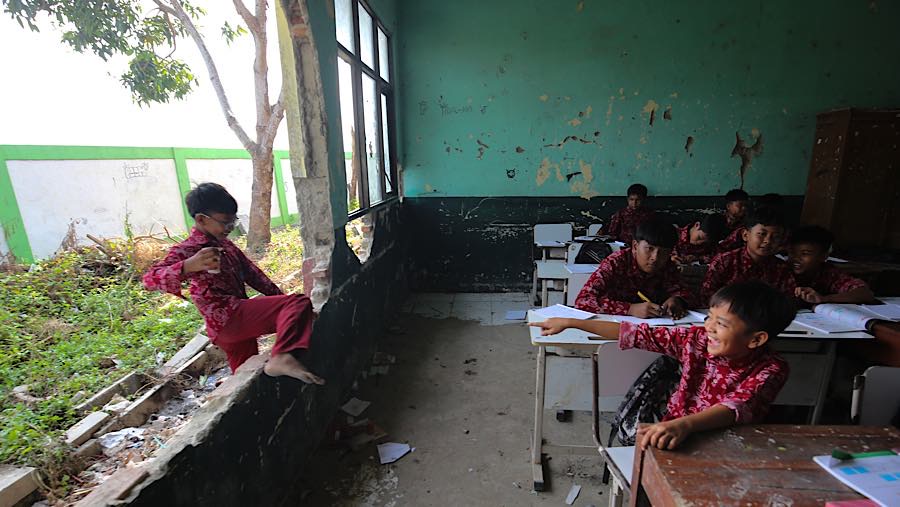 Siswa melewati tembok kelas yang jebol di SDN 3 Sukajadi, Kabupaten Bekasi, Jawa Barat, Kamis (24/9/2026). (Bloomberg Technoz/Andrean Kristianto)