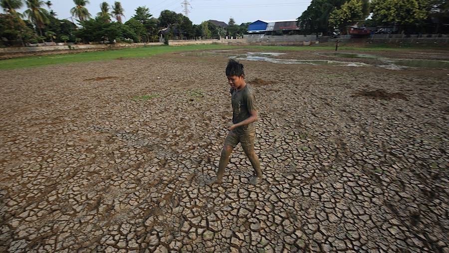 Warga berjalan di atas tanah yang retak Danau Cinere, Pangkalan Jati, Cinere, Jawa Barat, Jumat (25/9/2026) (Bloomberg Technoz/Andrean Kristianto)
