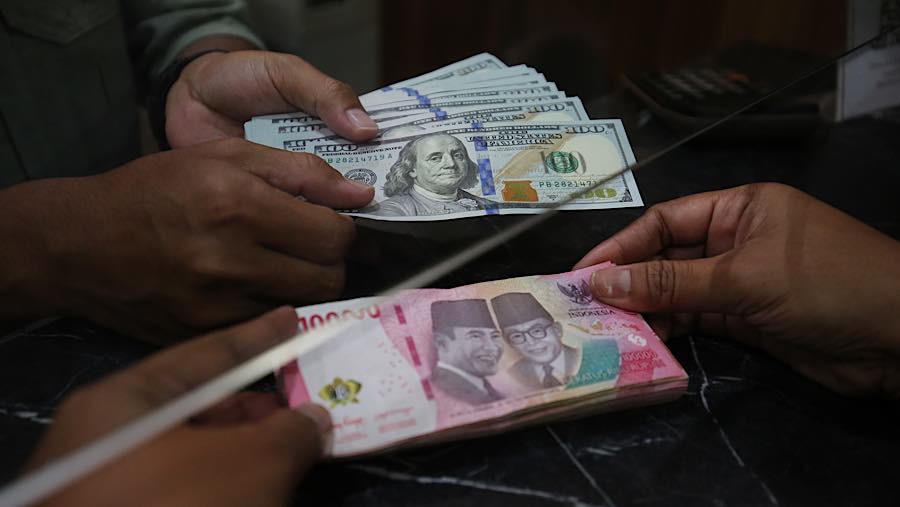 Nasabah menukarkan uang rupiah ke dolar AS di tempat penukaran uang asing di Jakarta, Selasa (29/9/2026). (Bloomberg Technoz/Andrean Kristianto)