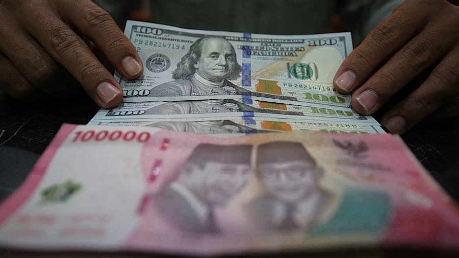 Karyawan merapihkan uang rupiah dan dolar AS di tempat penukaran uang asing di Jakarta, Selasa (29/9/2026). (Bloomberg Technoz/Andrean Kristianto)