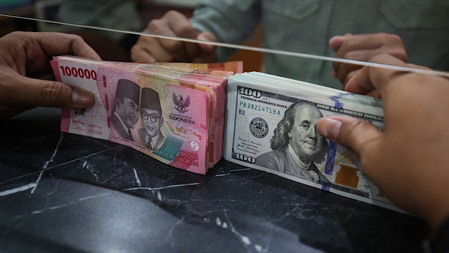 Karyawan merapihkan uang rupiah dan dolar AS di tempat penukaran uang asing di Jakarta, Selasa (29/9/2026). (Bloomberg Technoz/Andrean Kristianto)