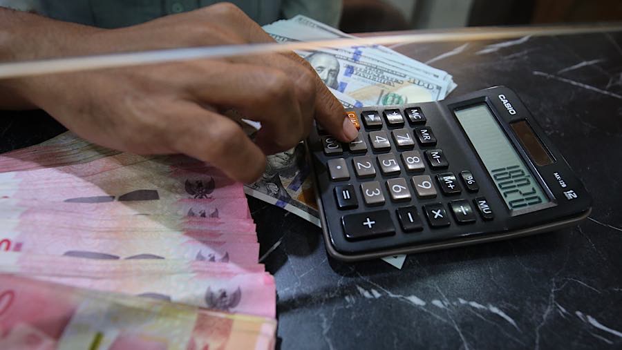 Karyawan menghitung uang rupiah dan dolar AS di tempat penukaran uang asing di Jakarta, Selasa (29/9/2026). (Bloomberg Technoz/Andrean Kristianto)