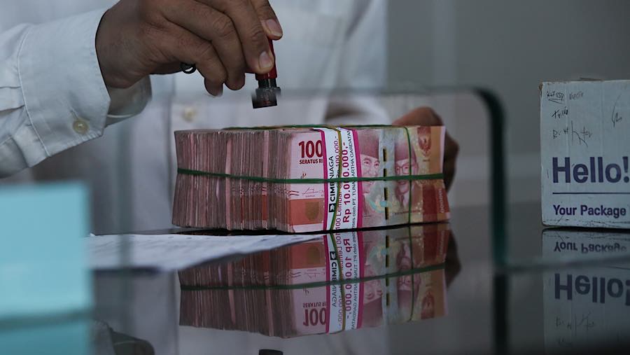 Karyawan menghitung rupiah di tempat penukaran uang asing di Jakarta, Selasa (29/9/2026). (Bloomberg Technoz/Andrean Kristianto)