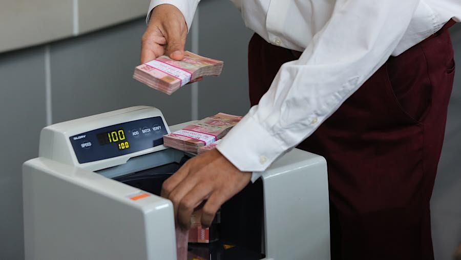 Karyawan menghitung rupiah di tempat penukaran uang asing di Jakarta, Selasa (29/9/2026). (Bloomberg Technoz/Andrean Kristianto)