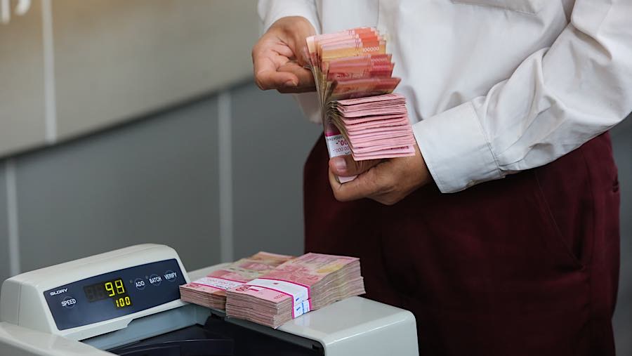 Karyawan menghitung rupiah di tempat penukaran uang asing di Jakarta, Selasa (29/9/2026). (Bloomberg Technoz/Andrean Kristianto)