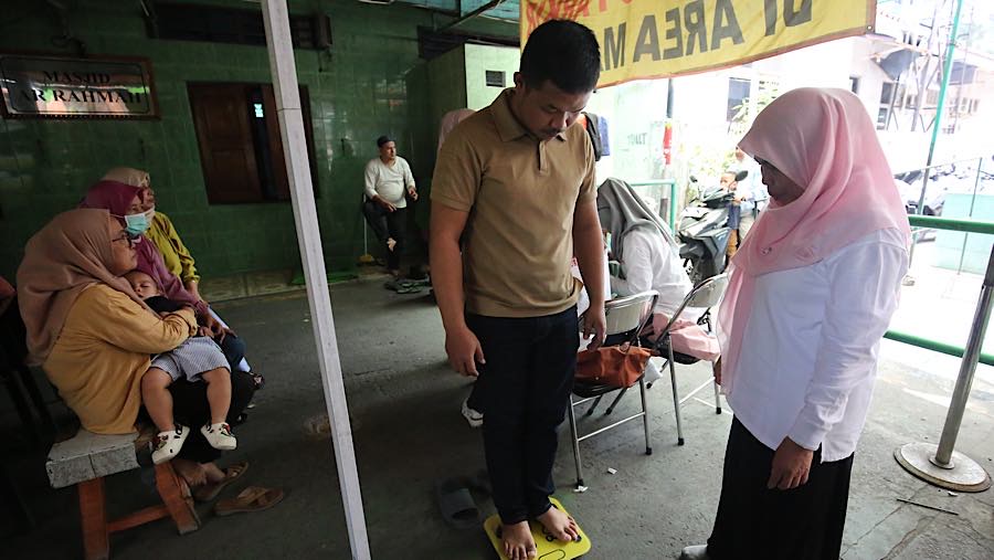 Petugas menimbang berat badan warga di Posyandu Mawar Kuning 2, Jakarta, Selasa (29/9/2026). (Bloomberg Technoz/Andrean Kristianto)