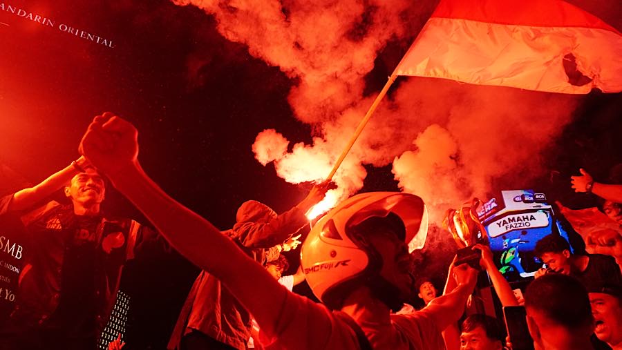 Sejumlah suporter menyanyikan lagu nasional, sementara suar dinyalakan untuk memeriahkan suasana. (Bloomberg Technoz/Andrean Kristianto)
