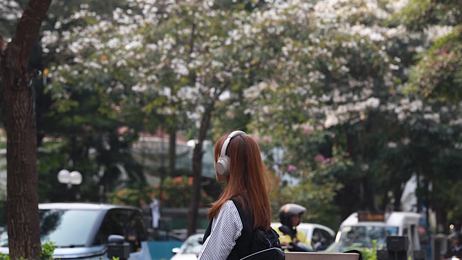 Warga duduk di pedestrian dekat Pohon Tabebuya di Jalan Cikini Raya, Jakarta, Jumat (9/10/2026). (Bloomberg Technoz/Andrean Kristianto)