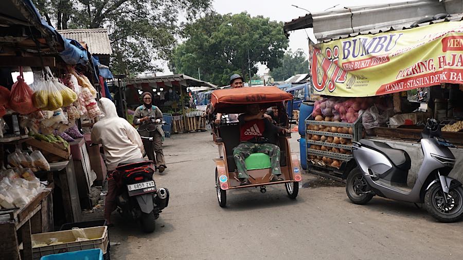 Pengemudi becak listrik mengantarkan penumpang di kawasan Pasar Kemiri, Depok, Jawa Barat, Senin (12/10/2026). (Bloomberg Technoz/Andrean Kristianto)