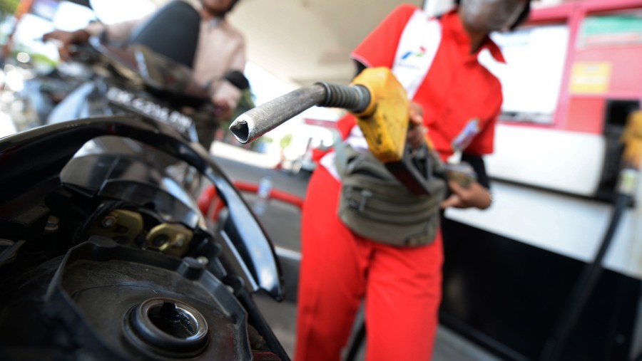 Petugas memegang nosel pompa BBM saat mengisi bahan bakar sepeda motor pelanggan di SPBU Pertamina di Nusa Dua, Bali./Bloomberg-Dimas Ardian