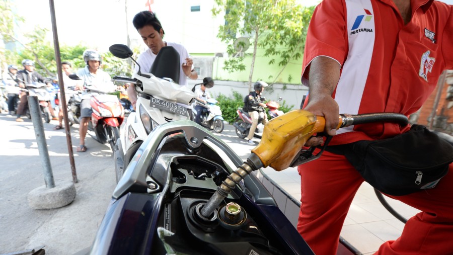 Petugas mengisi BBM sepeda motor seorang pelanggan, sementara pengendara lain mengantre di sebuah SPBU Pertamina di Nusa Dua, Bali./Bloomberg-Dimas A.