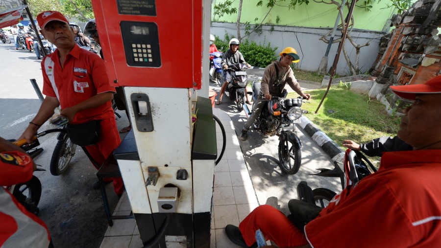 Petugas mengisi BBM sepeda motor pelanggan sementara pengendara lain mengantre di SPBU Pertamina di Nusa Dua, Bali./Bloomberg-Dimas Ardian