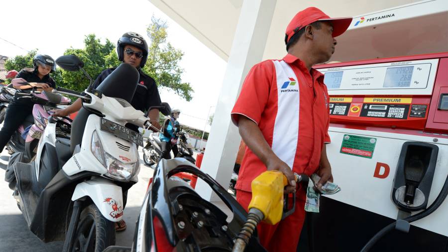Petugas mengisi BBM ke sepeda motor, sementara pengendara lain mengantre di SPBU Pertamina di Nusa Dua, Bali. (Dimas Ardian/Bloomberg)