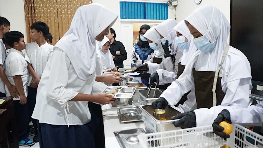 Satu per satu siswa maju mengambil makanan sesuai takaran yang telah ditentukan. (Bloomberg Technoz/Andrean Kristianto)