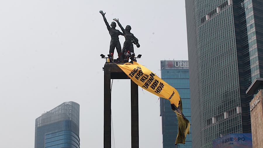 Aktivis Greenpeace melakukan aksi di atas Patung Selamat Datang, Bundaran HI, Jakarta, Selasa (20/10/2026). (Bloomberg Technoz/Andrean Kristianto)